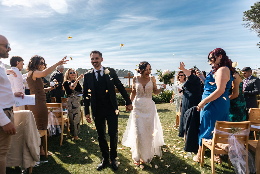 Bride and groom walking down the aisle covered in confetti
