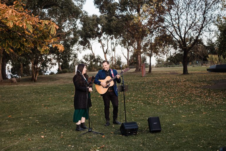 Singer and guitar player performing on the grass outside