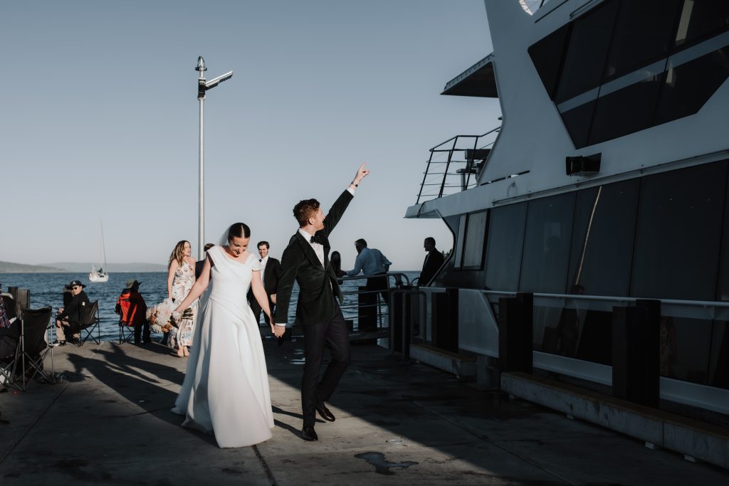 Bride and groom disembarking a white catamaran with their guests